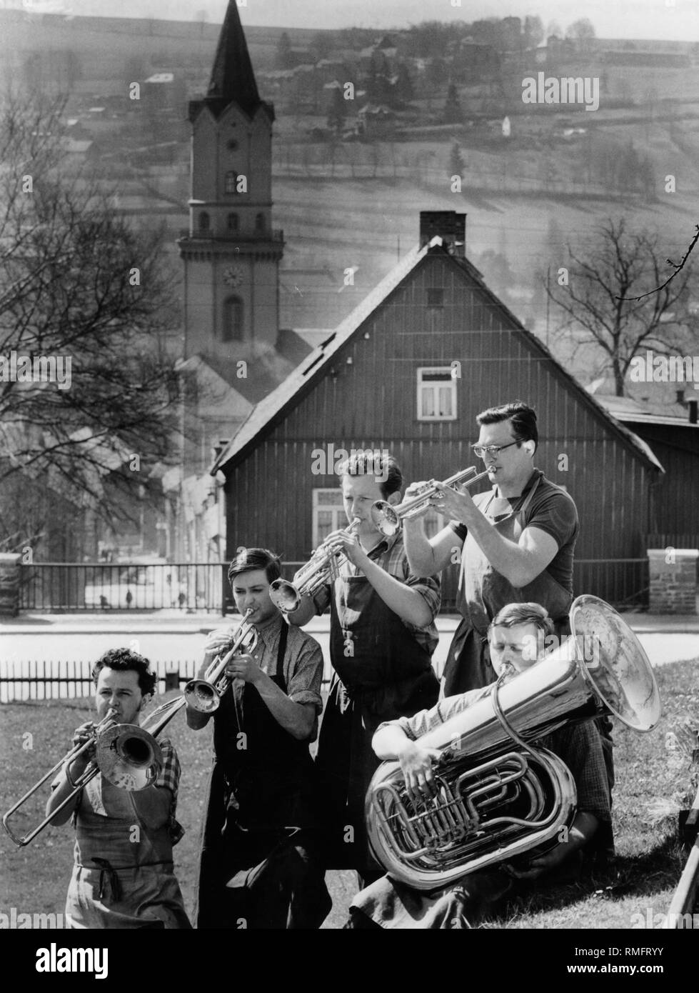 Five brass instruments of a brass band in the Vogtland music town Markneukirchen in Saxony. In the background the tower of the consecrated St. Nicholas Church. Stock Photo