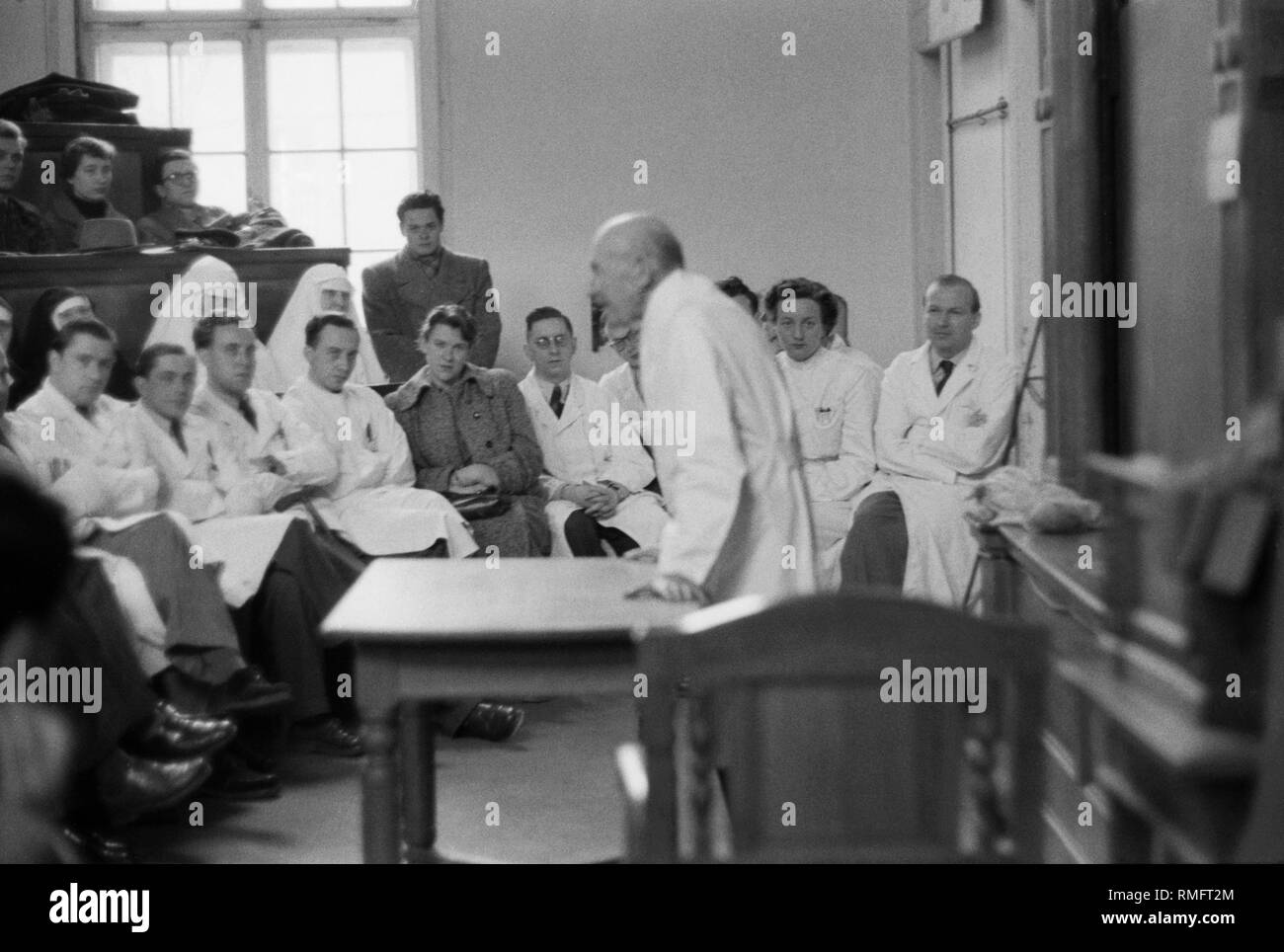 Privy Council Professor med. Carl Wessely giving his farewell lecture shortly before his death in the eye clinic at Pettenkoferstrasse, Munich. He was chairman of the Deutsche Ophthalmologische Gesellschaft and founder of the Vereinigung Bayerischer Augenaerzte (Association of Bavarian Ophthalmologists). Behind, physician colleagues and in front of the students also two nuns of the 'Kongregation der Schwestern des Allerheiligsten Erloesers' ('Congregation of the Sisters of the Most Holy Redeemer'). Stock Photo
