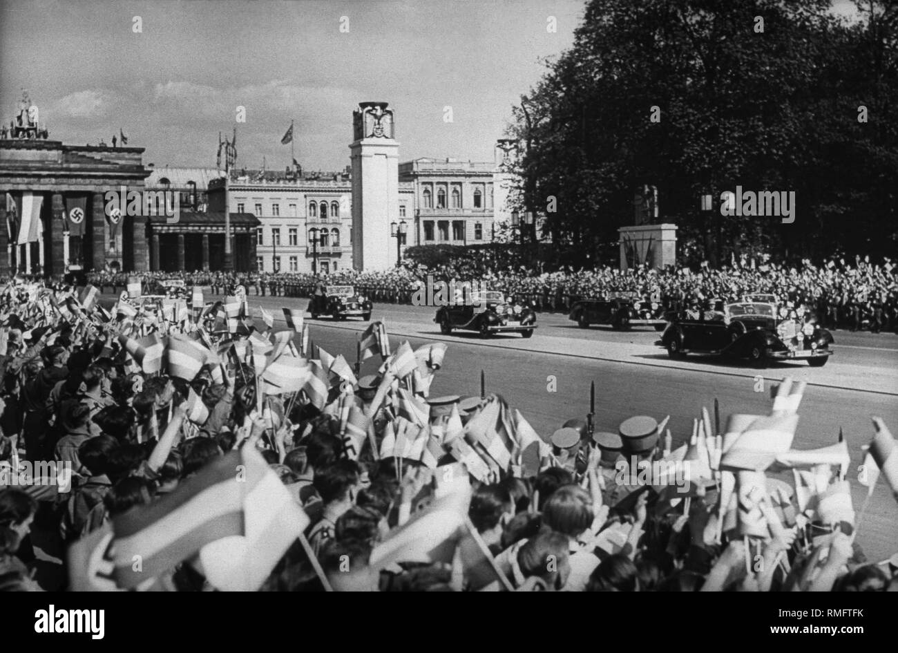 Adolf Hitler drives in the front car of the convoy to receive the  Condor Legion, who have returned from the Spanish Civil War, in the Lustgarten Berlin. The people in Strasse Unter den Linden (to the left in the background the Brandenburg Gate) cheer him. Stock Photo