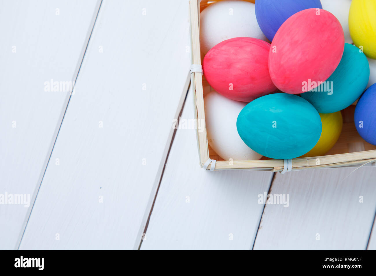 Easter, holidays, tradition and object concept - close up of colored easter eggs in basket Stock Photo