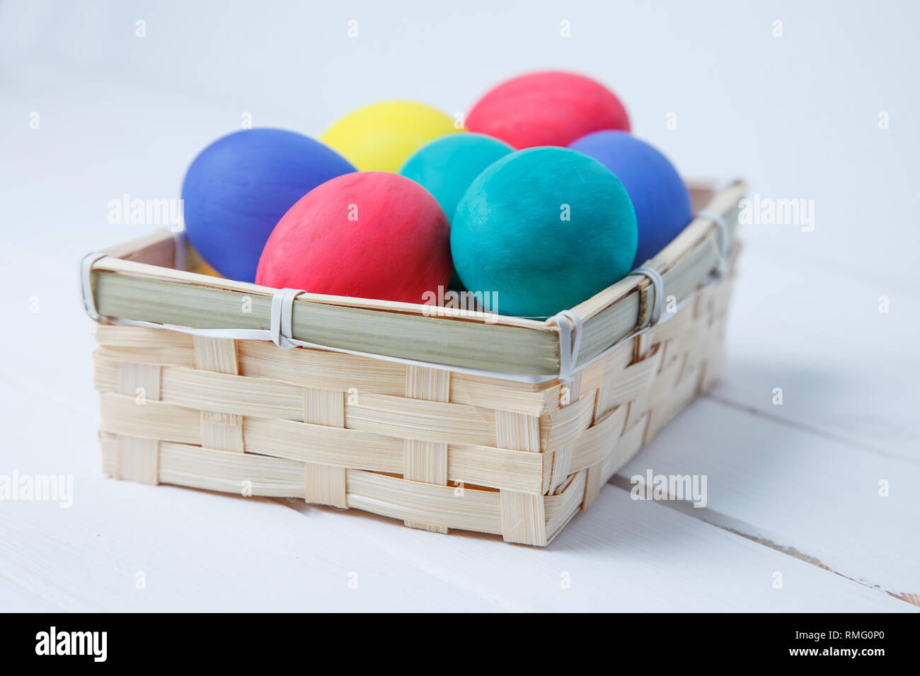 Easter, holidays, tradition and object concept - close up of colored easter eggs in basket Stock Photo