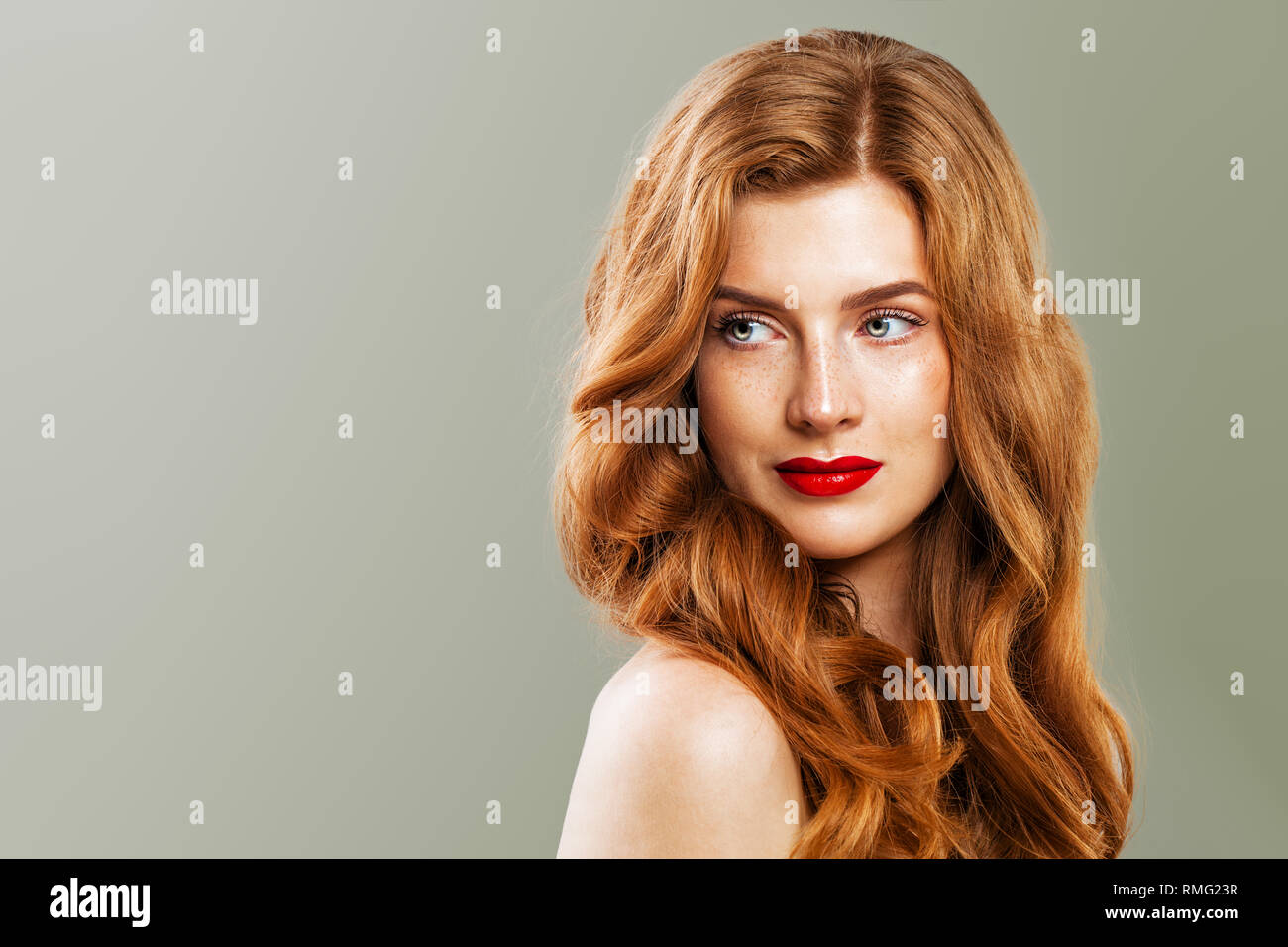 Young beautiful red haired woman. Redhead girl with ginger curly hairstyle on green background Stock Photo