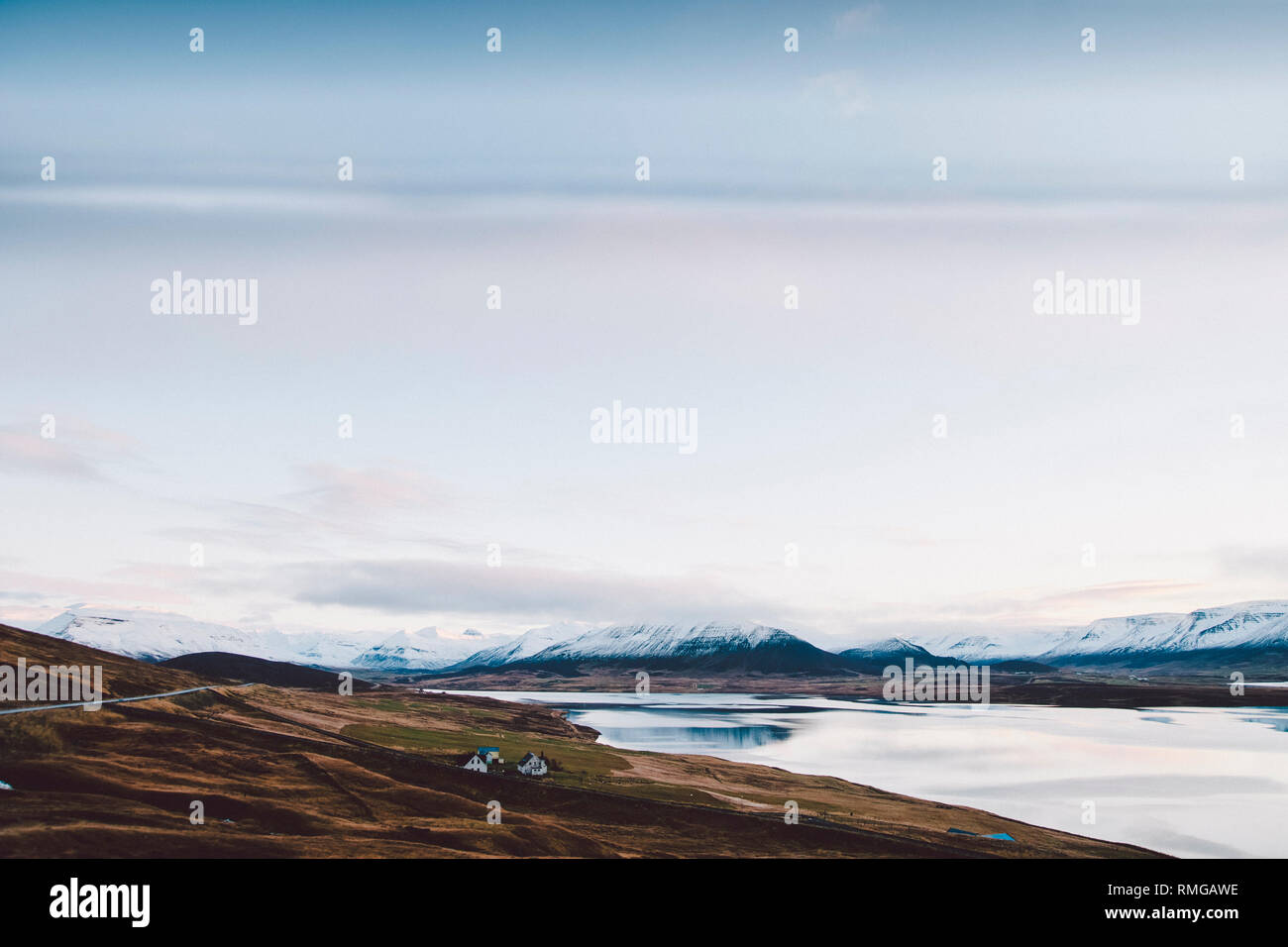 Village with farms in a rural area of the mountains of Iceland, with snowy mountains in the background. Stock Photo
