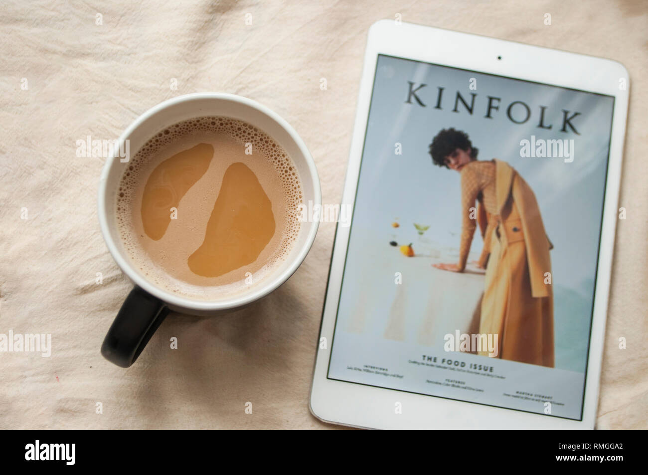 Morning routine concept. A cup of coffee and tablet with Kinfolk magazine cover. Stock Photo