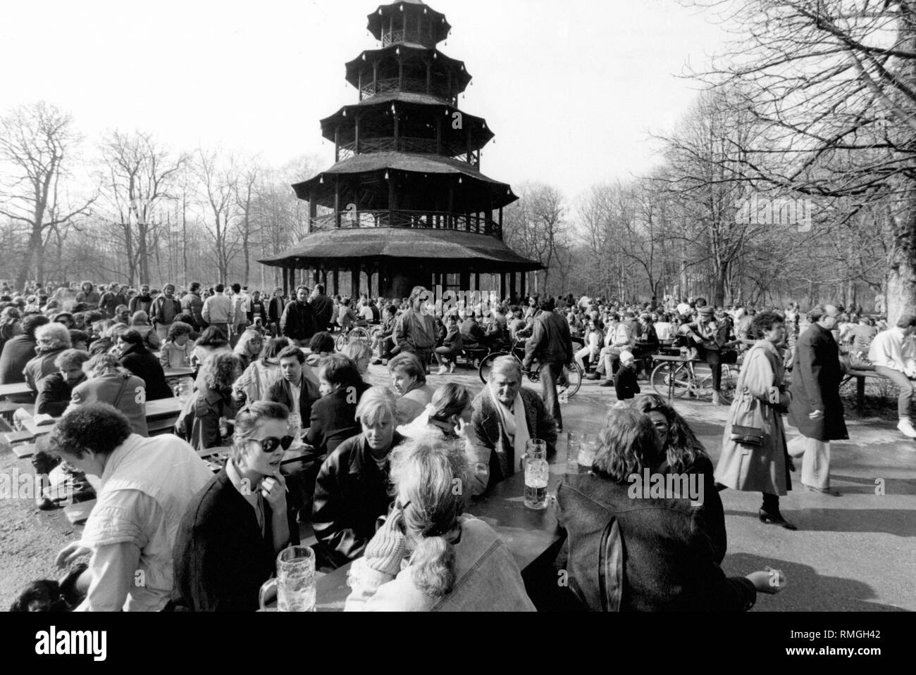 In spring many people are sitting in the beer garden at the Chinese Tower in the Englischer Garten in Munich. Stock Photo