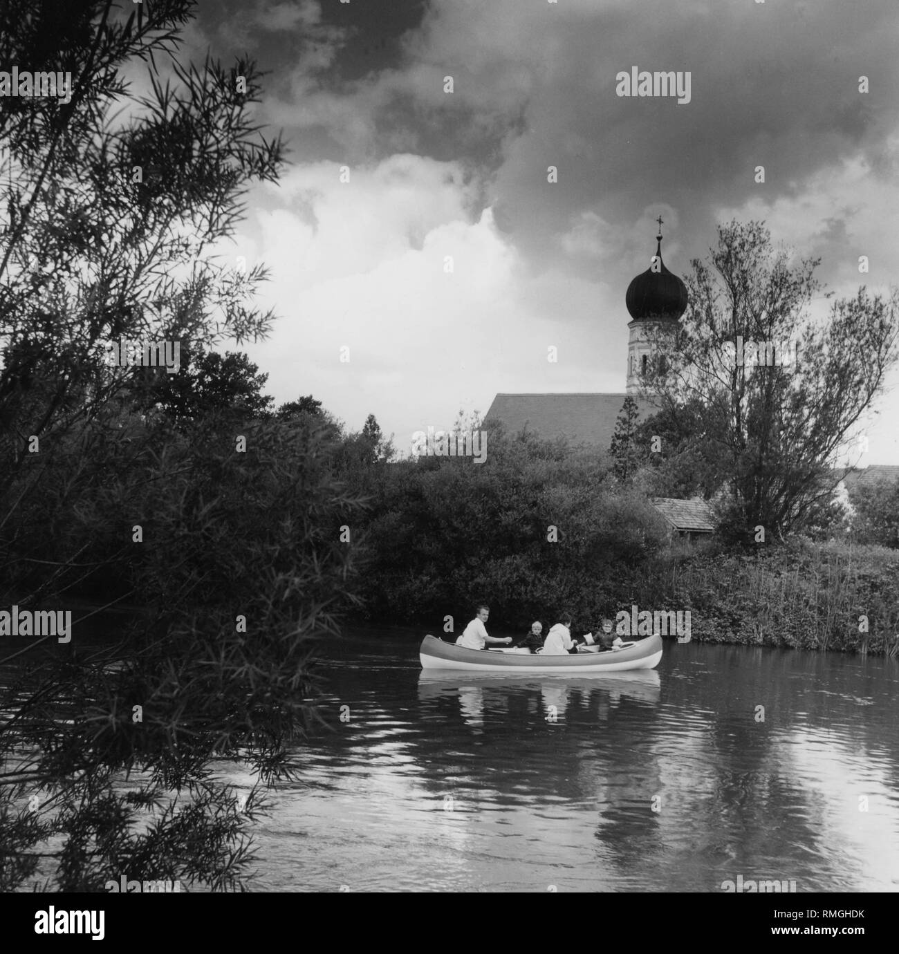 People in a dinghy on the river Amper near Schoengeising with the Parish Church St. Johannes Baptist, around 1980. Stock Photo
