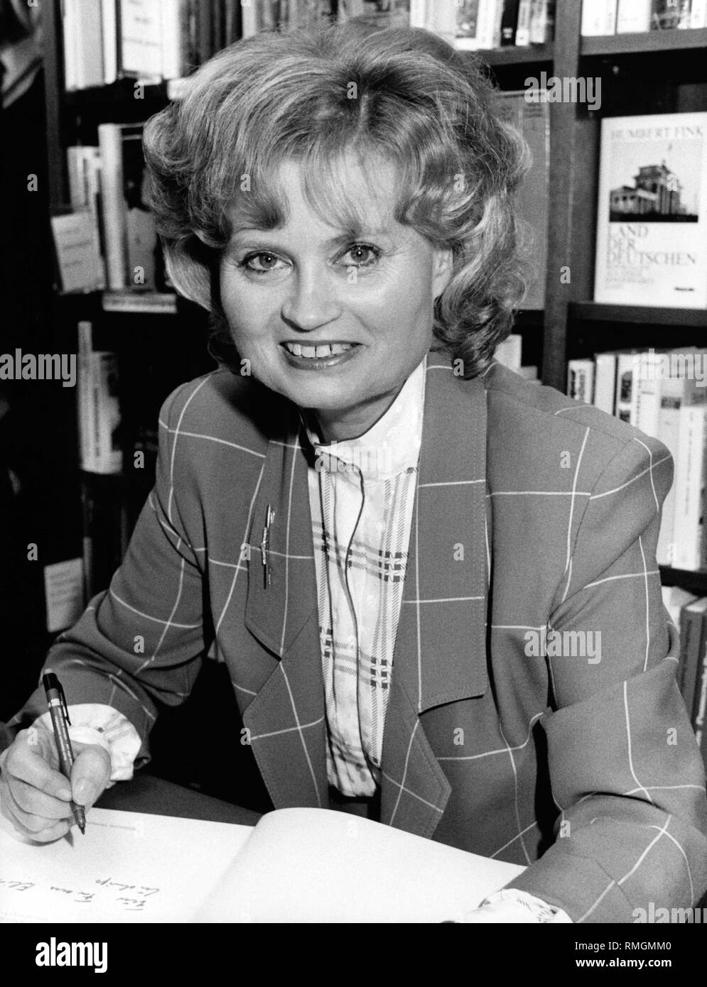 Hannelore Kohl signs in a bookstore the cookbook published by her 'Was Journalisten anrichten', in which well-known German journalists present cooking recipes. The profit will go to her foundation in favor of accident victims Kuratorium ZNS, (today: ZNS - Hannelore Kohl Stiftung fuer Verletzte mit Schaeden des Zentralen Nervensystems - ZNS - Hannelore Kohl Foundation for Patients with Damage of the Central Nervous System). In the bookshelf behind there is, among others, a work by Humbert Fink: 'Land der Deutschen - Reportagen aus einem sonderbaren Land'. Stock Photo