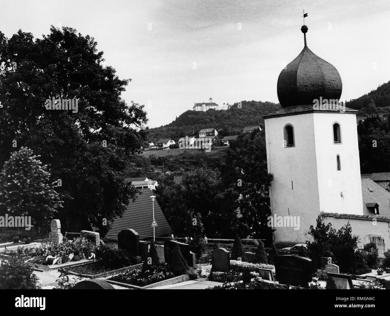 The cemetery with the onion dome of the protestant church in Heiligenstadt. In the background is the Greifenstein Castle. Stock Photo