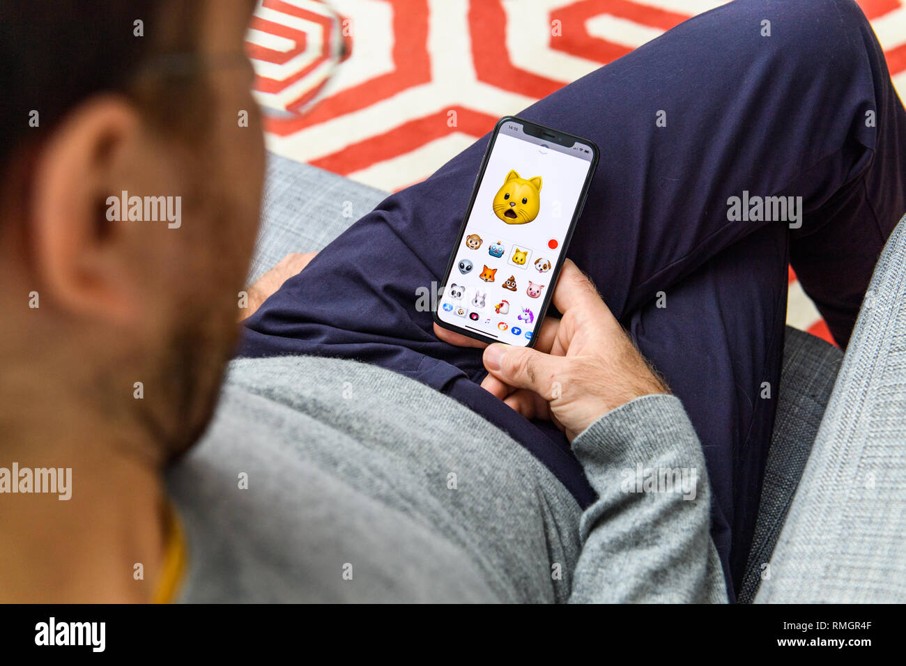LONDON, UK - SEP 21, 2018: Man using the new astonished cat pet AR Memoji emoji face on Apple iPhone Xs with the immense OLED retina display and a12 bionic chip, Stock Photo