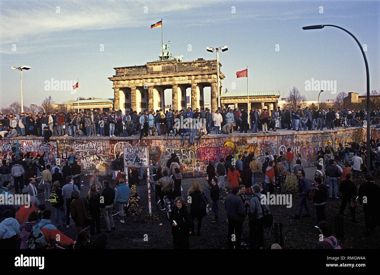 Thousands of East and West Berliners celebrate the opening of the border on the night of November 9, 1989, on the Berlin Wall at the Brandenburg Gate. Stock Photo