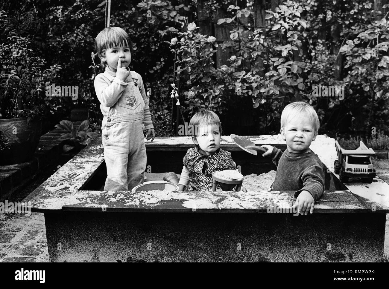 Three children playing in the sandbox Stock Photo - Alamy