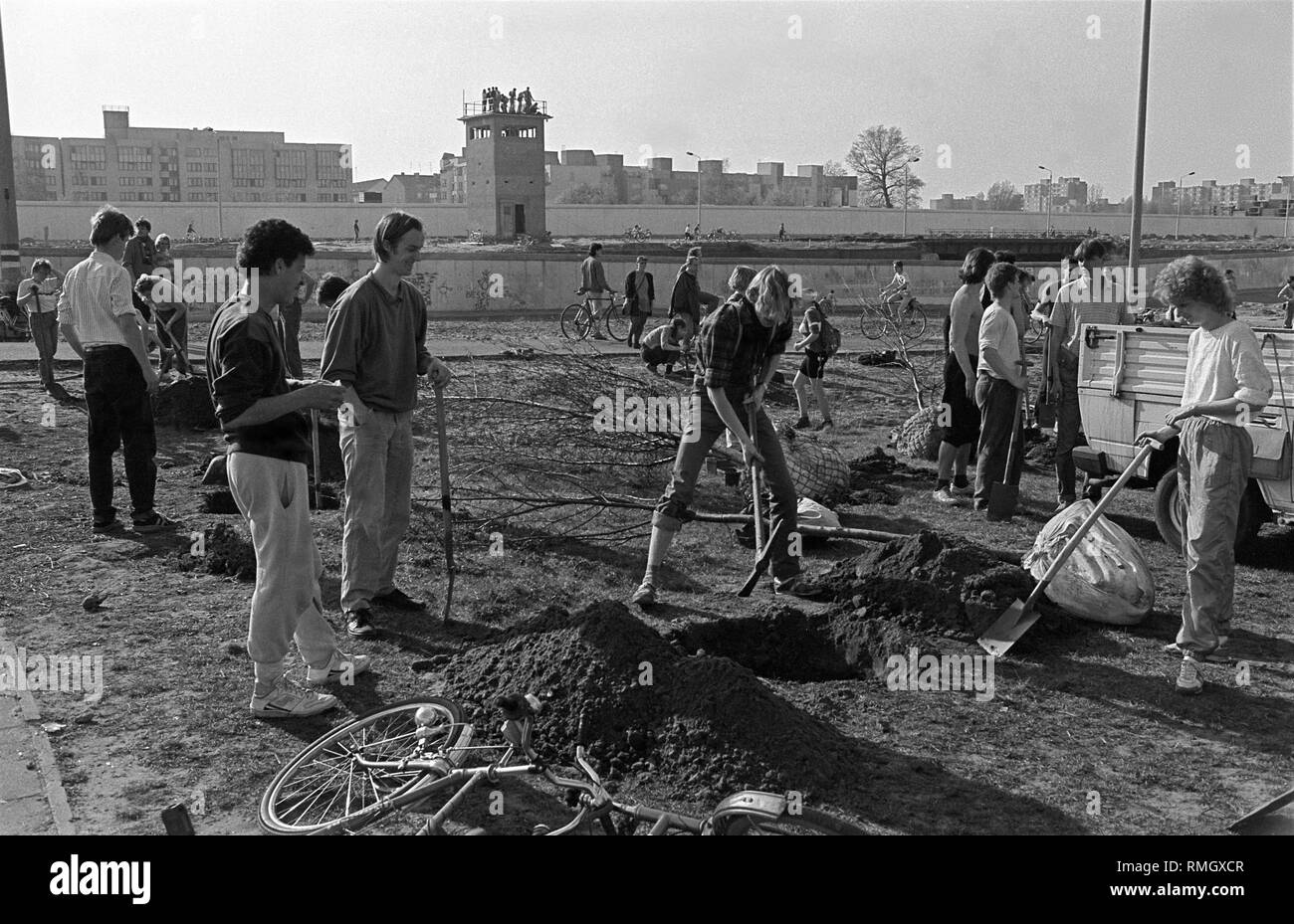 Proponents of the green belt during tree planting at the border strip at Falkplatz (later Mauerpark), after a bicycle demonstration from the Rotes Rathaus to Falkplatz. In the background, a watchtower of the border troops (at the Gleimtunnel), Germany, Prenzlauer Berg, Berlin, April 1, 1990. Stock Photo