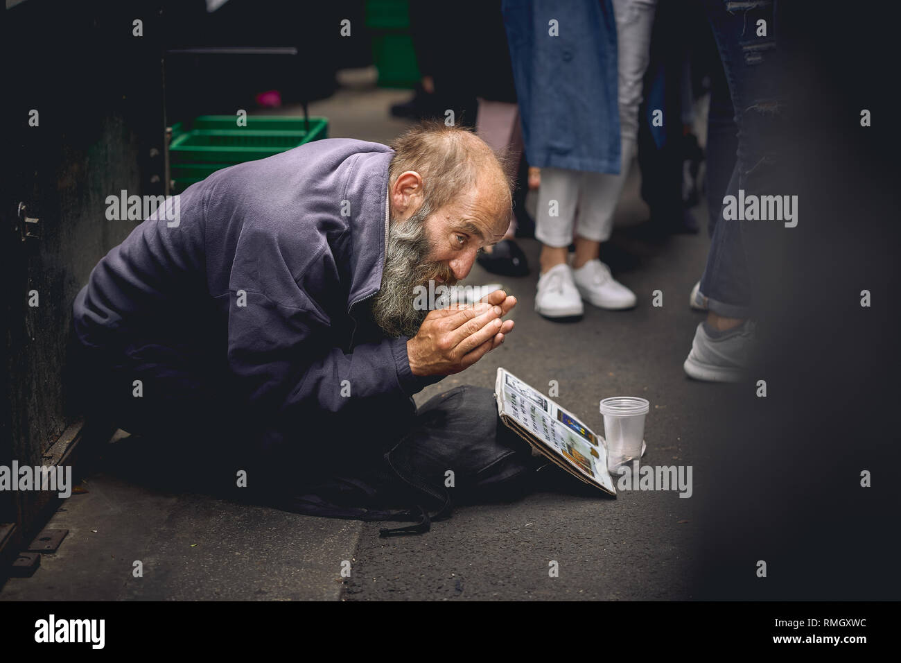 London, UK - June, 2018. An old homeless man begging for help in a crowded Borough Market. Stock Photo