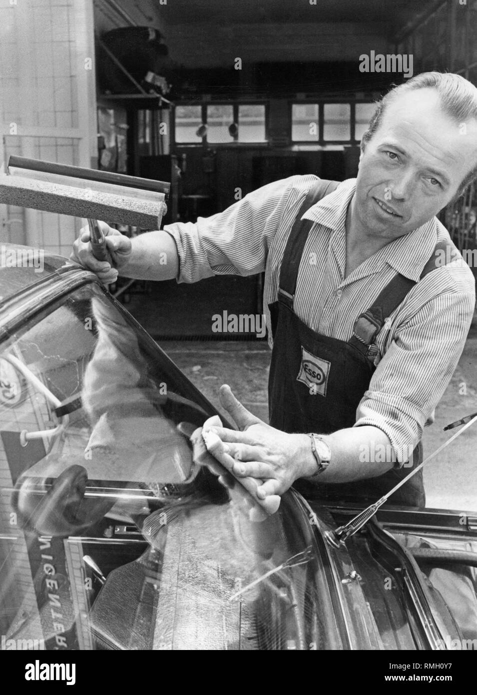 A gas station attendant cleans a windshield at an Esso gas station in