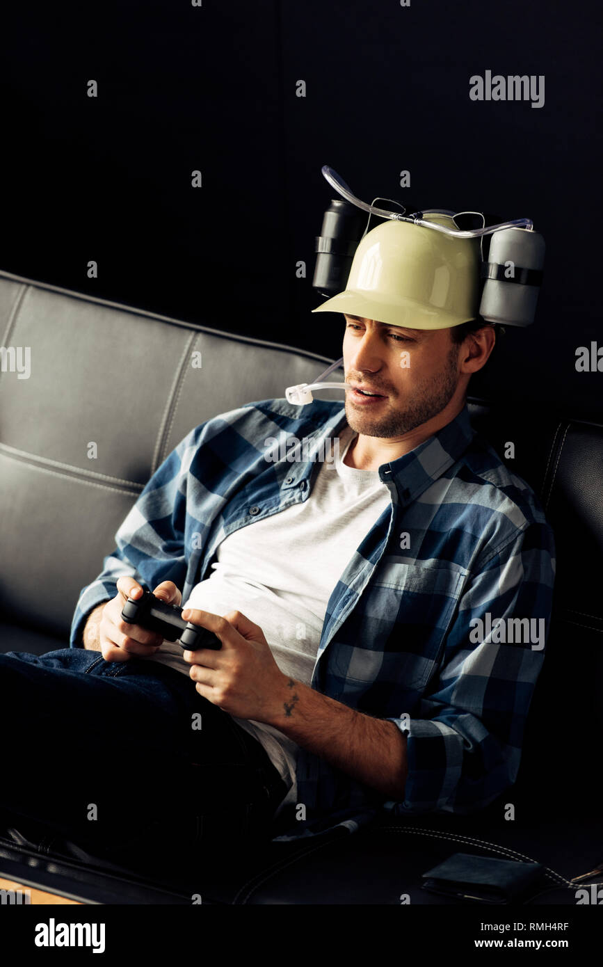 handsome man drinking from beer helmet and playing video game Stock