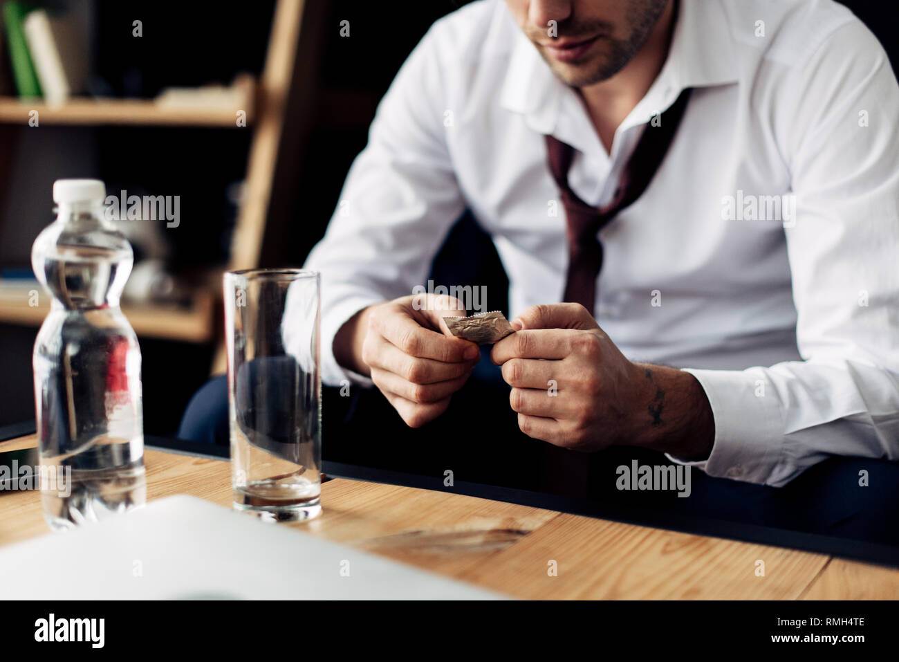 cropped view of businessman holding pill in hands near glass of water Stock Photo