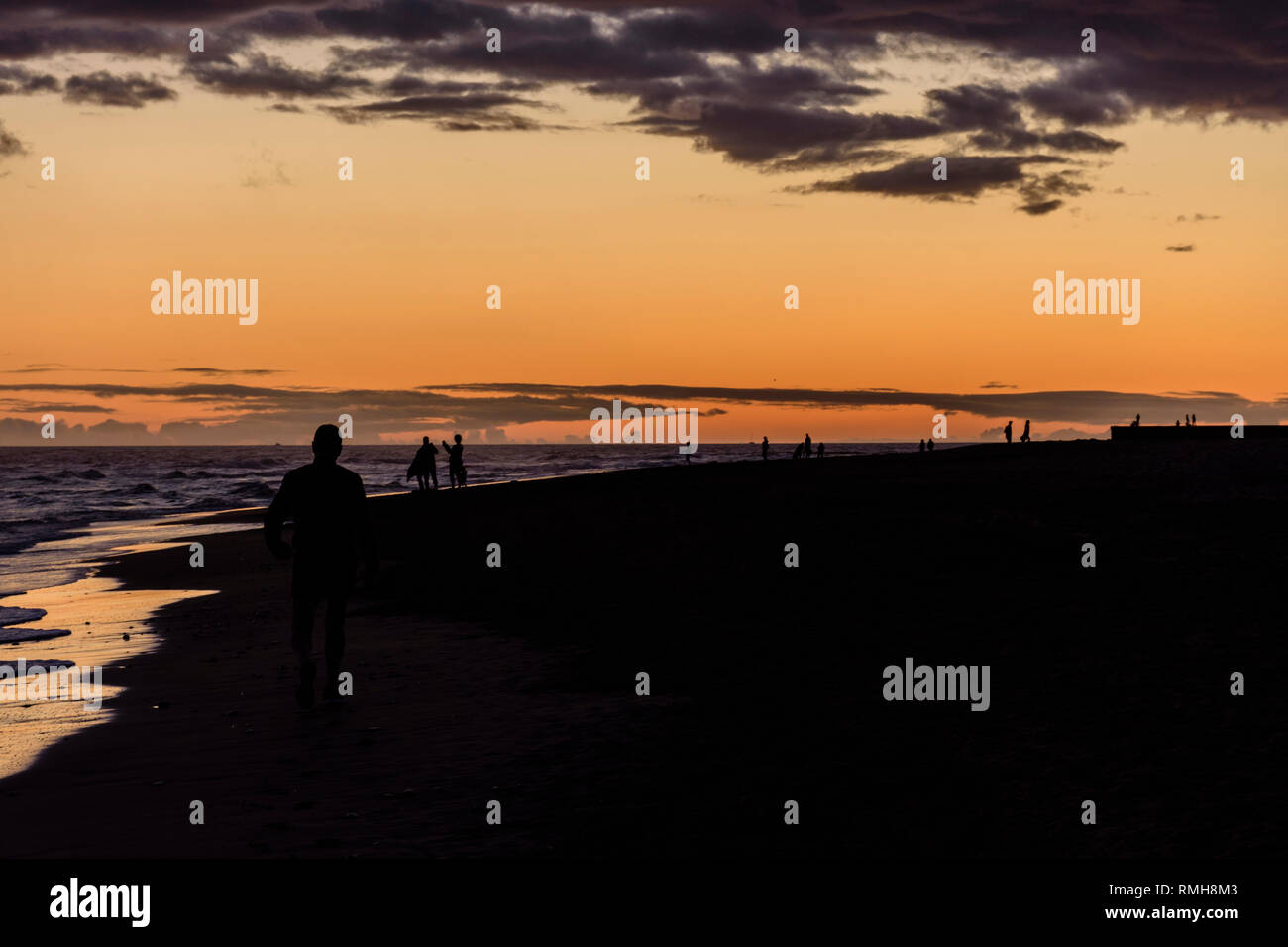 people silhouette walking on the beach during sunset Stock Photo - Alamy