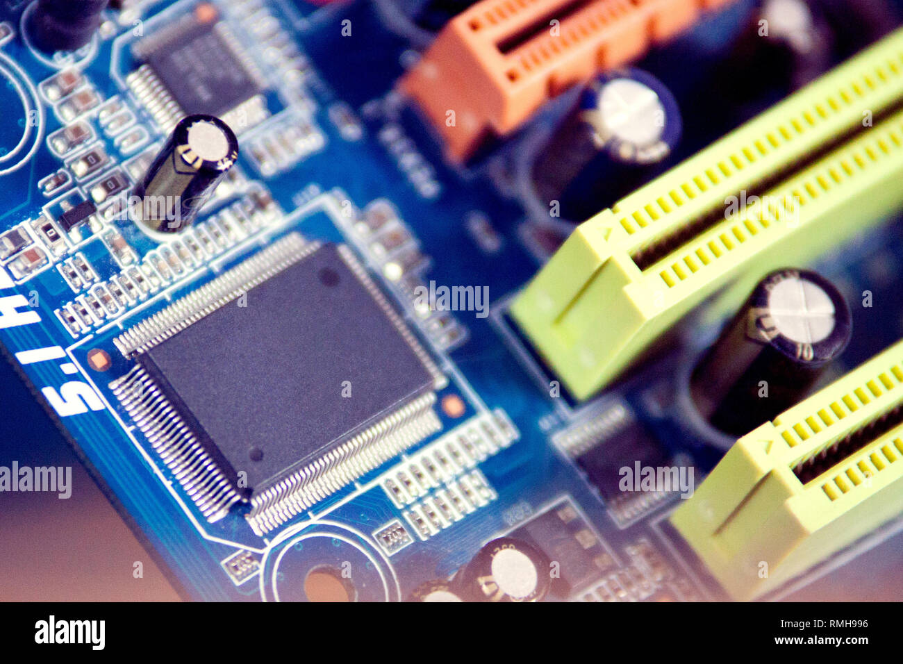 Close up computer motherboard microchip. texture background, toned. yellow and orange pci ex slots. chip mockup. Stock Photo