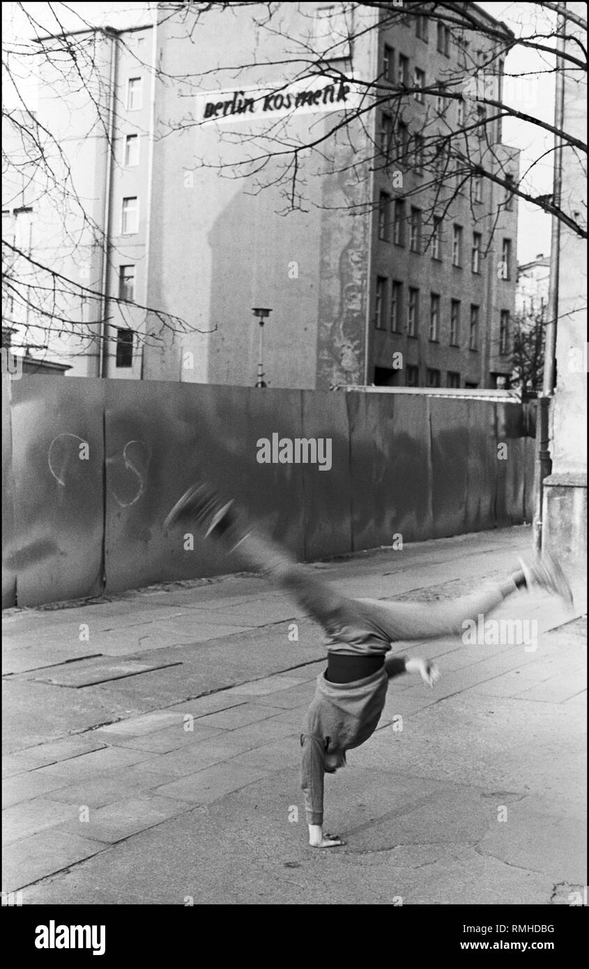 Germany, Berlin, 21 April,1988: Handstand, Anklamer Strasse, construction site fence, advertisement company (VEB) Berlin Kosmetik. Stock Photo