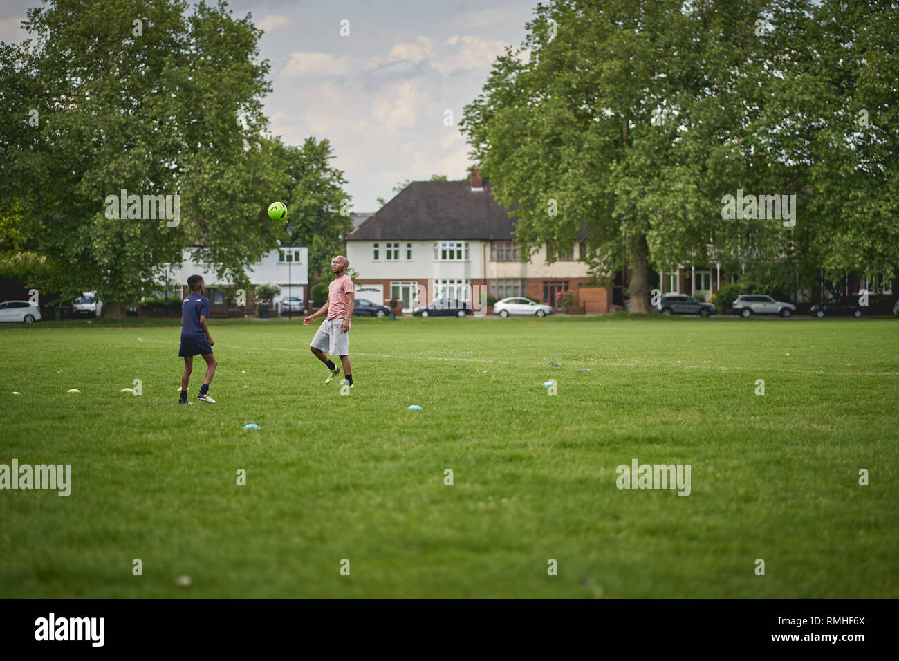 London, UK - June, 2018. Two young men playing football in a park in ...