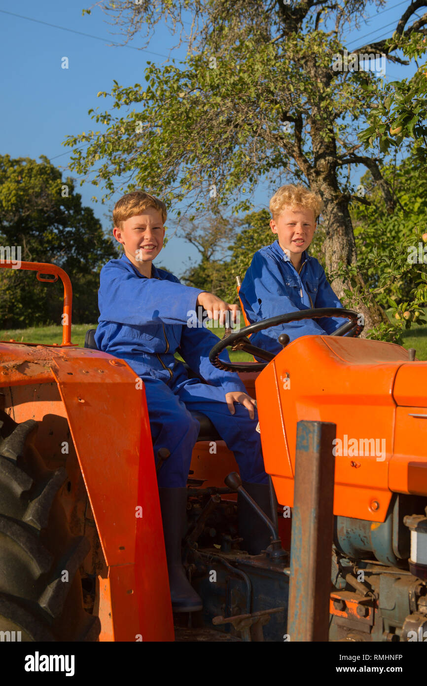 Farm boys riding on orange tractor Stock Photo Alamy