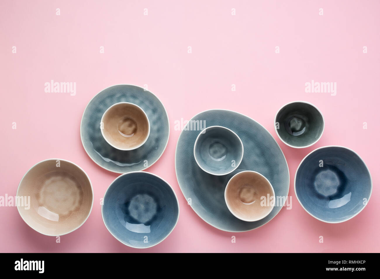 Beautiful blue, grey, beige dinnerware, plates bowls on pink table, top view, selective focus Stock Photo