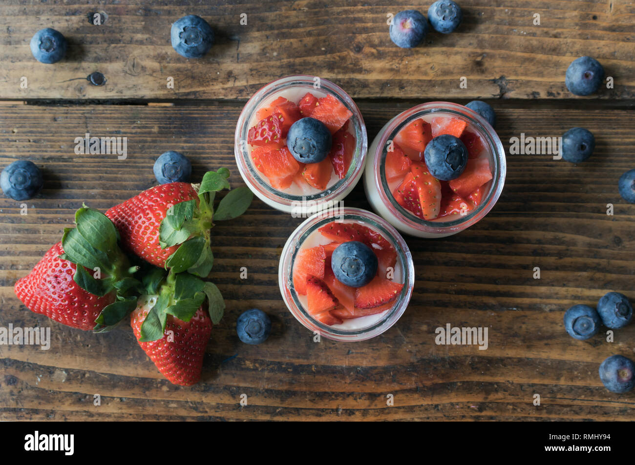 Homemade strawberry yogurt with jam and pieces of fruit on a wooden board. View from above Stock Photo
