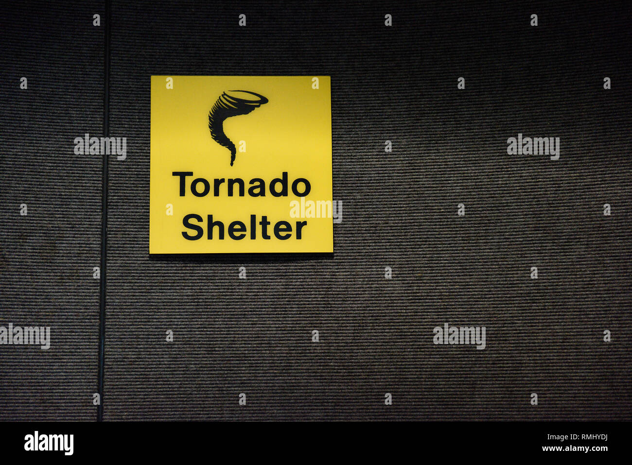 Tornado shelter yellow sign designating a safe room area, with tornado or twister icon. Stock Photo