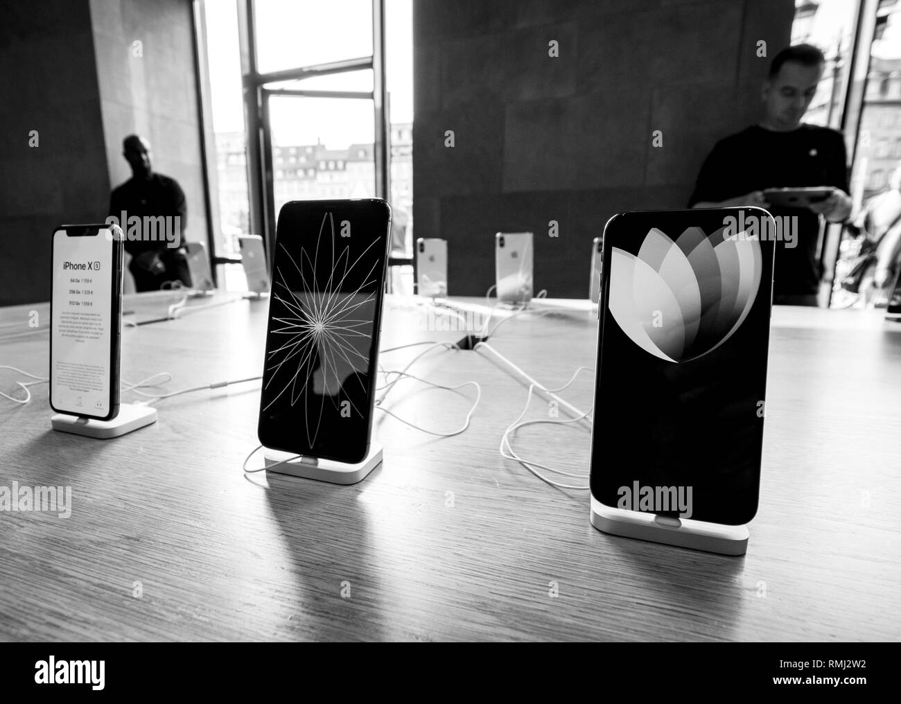 STRASBOURG, FRANCE - SEP 21, 2018: Row of new iPhones in Apple Store with customers people buying admiring the new latest iPhone Xs and Xs Max preorder for Xr and Watch Series 4 wearable - black and white Stock Photo