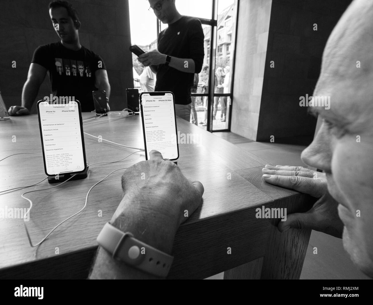 STRASBOURG, FRANCE - SEP 21, 2018: Close-up of senior man in Apple Store deciding admiring the new latest iPhone Xs and Xs Max pre order for Xr and Watch Series 4 wearable black and white Stock Photo