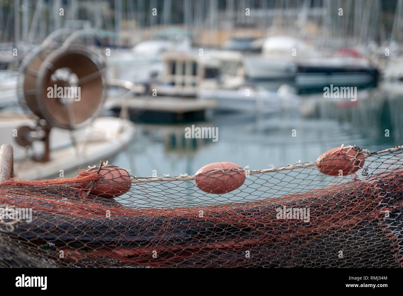 Red fishing net with red buoys. Blurred background on the harbor. Stock Photo