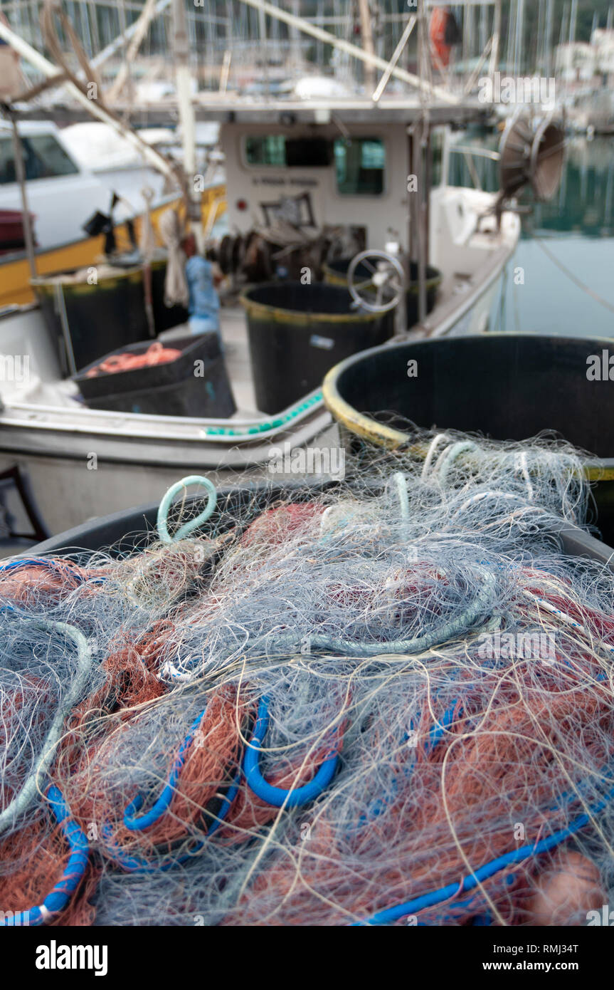 Close up on colored fishing nets. In the background a blurred fishing boat Stock Photo