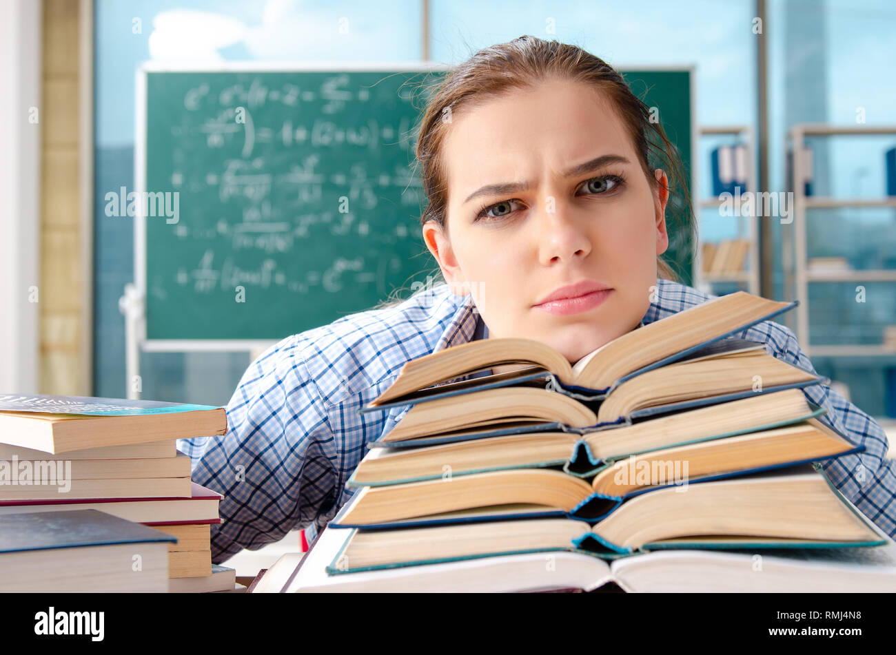 Female student with many books sitting in the classroom Stock Photo - Alamy