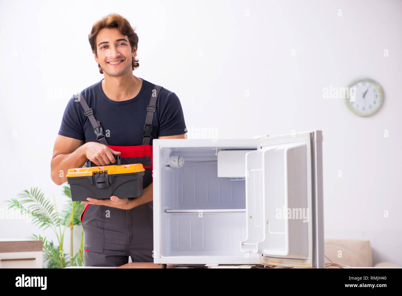 Young handsome contractor repairing fridge Stock Photo