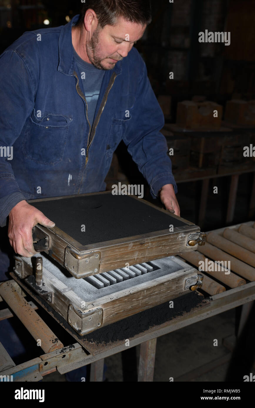 A foundryman fits together the two halves of a mould for making a fire grate from molten iron. Stock Photo