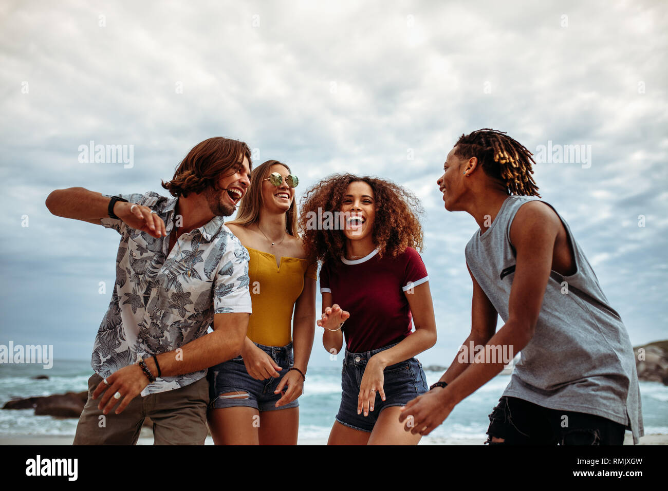 Smiling group of friends enjoying on the beach. Multi-ethnic men and women having fun outdoors along the beach. Stock Photo