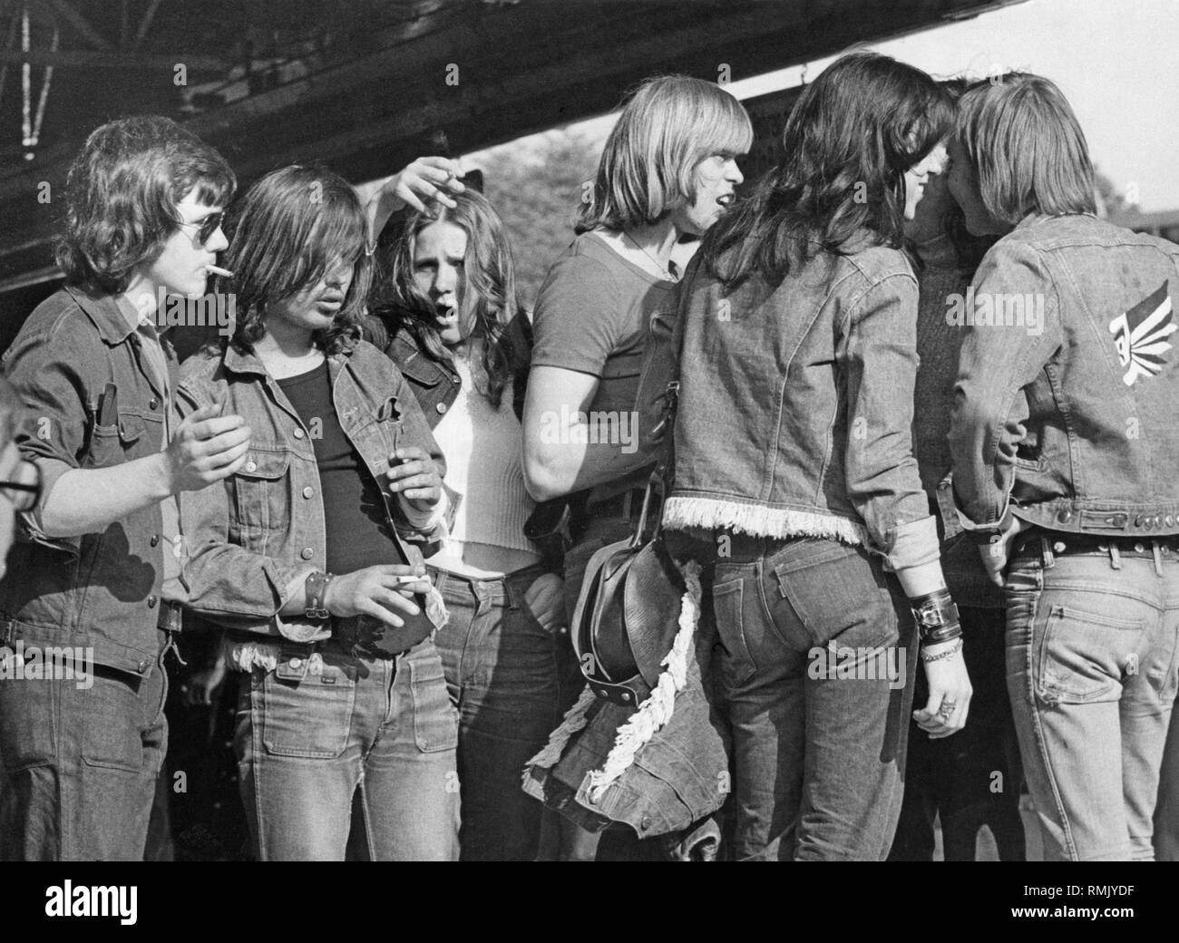 Teenagers, mostly wearing denim, stand in a group. Stock Photo