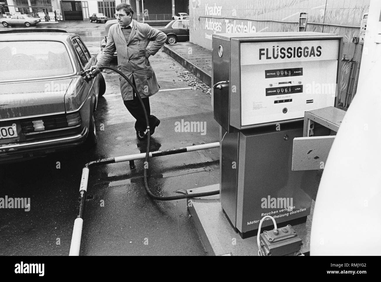 A man refueling his Mercedes E-Class (W123 series) with liquid gas (LPG - Liquified Petroleum Gas) Stock Photo