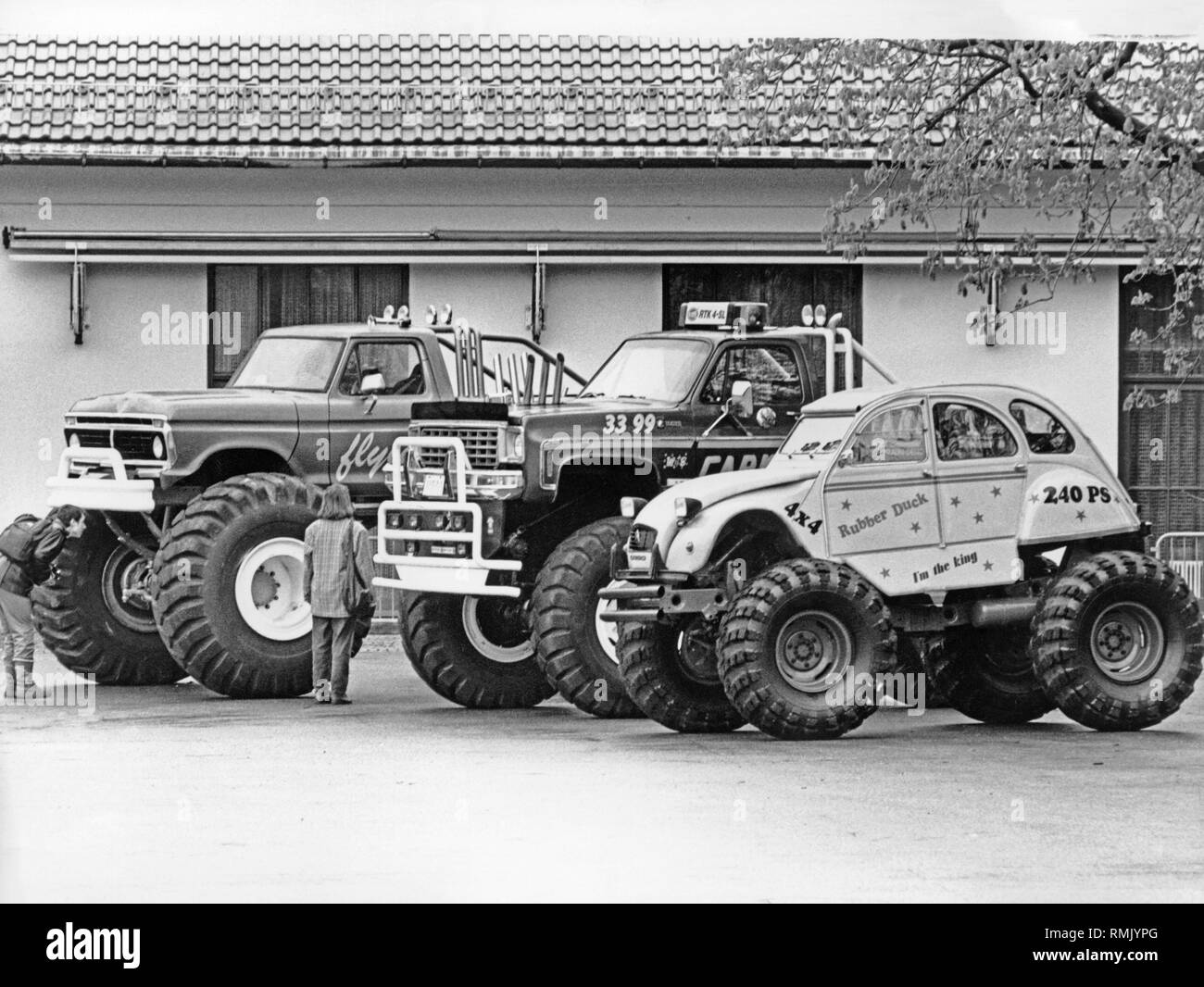 Three cars that were displayed at the largest European SUV exhibition in Munich. In front a Citroen 2CV with truck tires and a 240 HP engine. In the middle a Chevrolet Cheyenne, year of construction 1976. In the back, a Ford F-100, year of construction 1973. Stock Photo