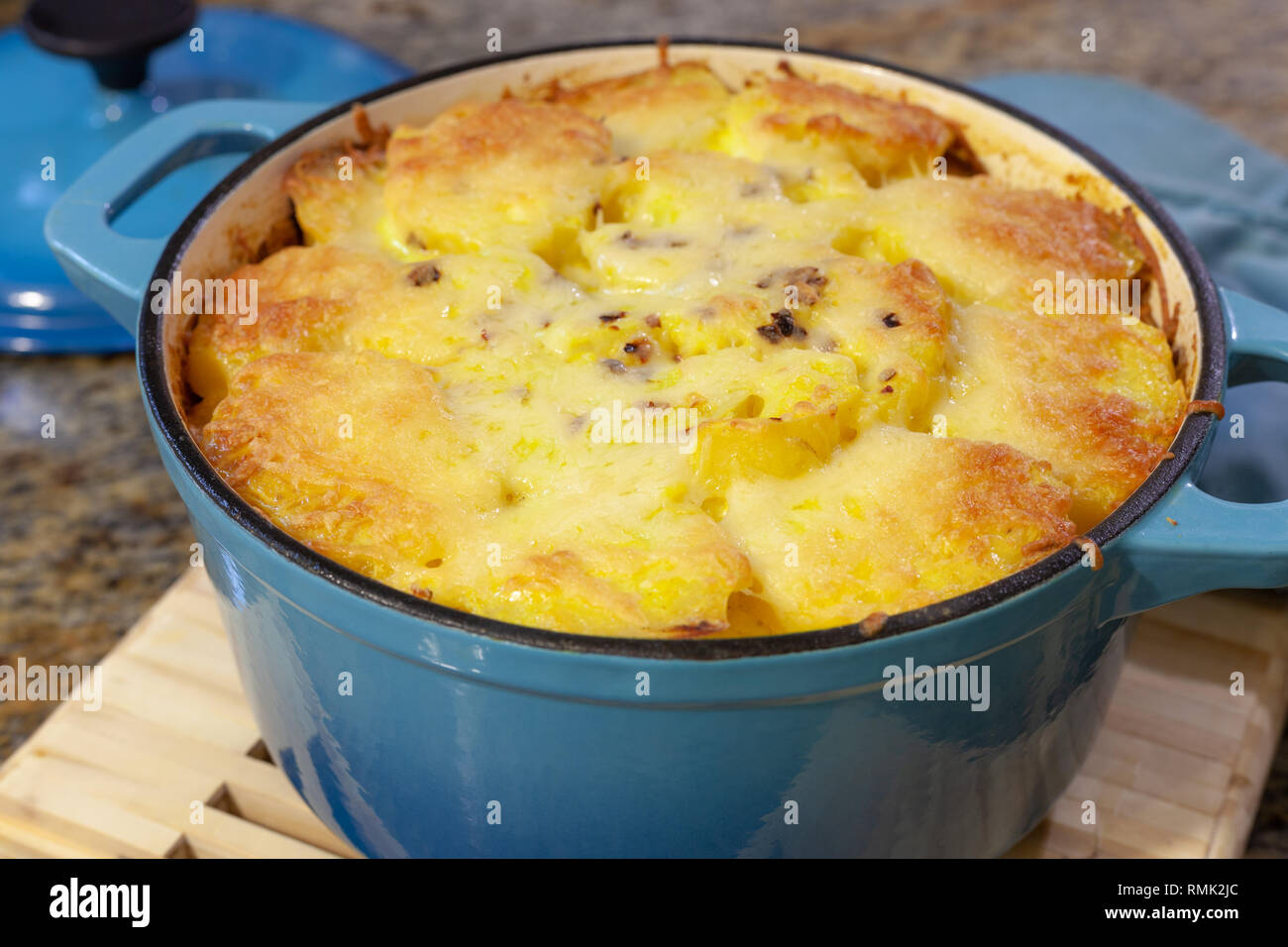 Baked Au Gratin potatoes in blue cast iron baking pot with melted
