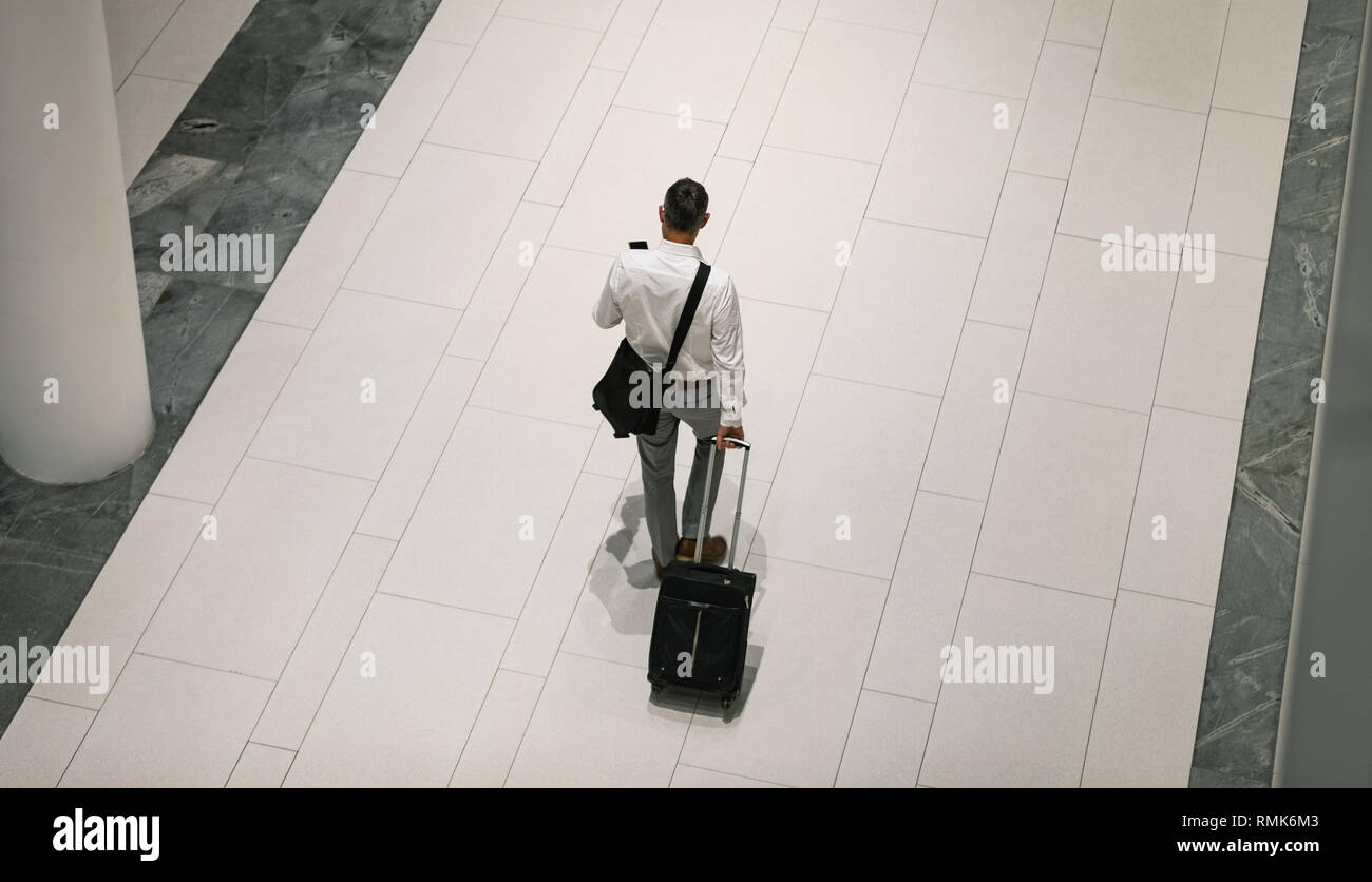 Businessman with travel suitcase walking in the corridor Stock Photo
