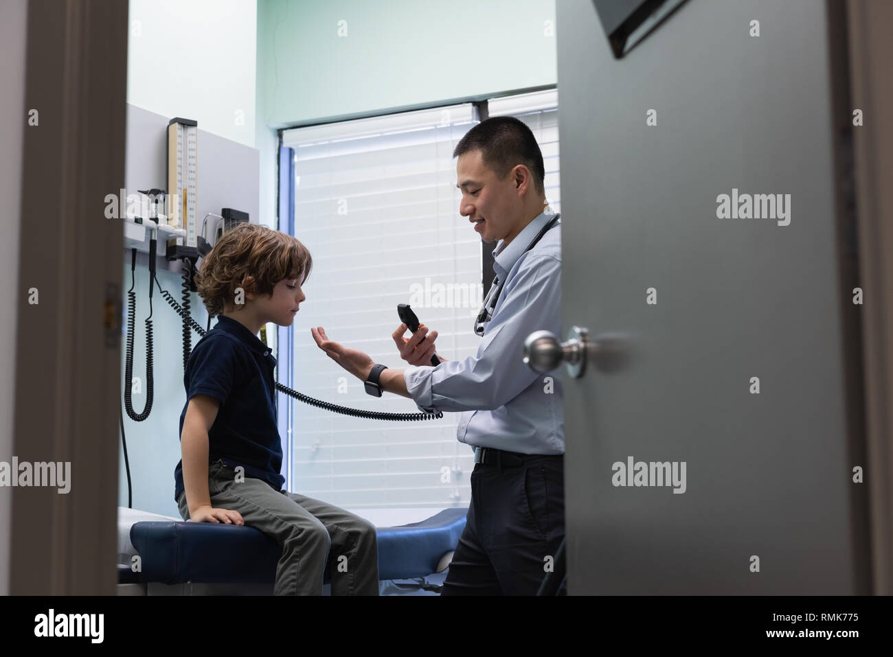 Young asian male doctor examining a caucasian boy patient with medical tool Stock Photo