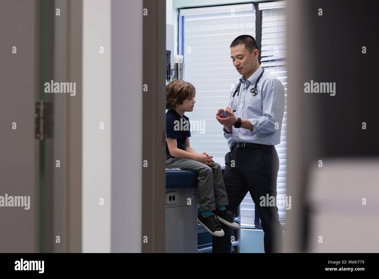 Young asian male doctor interacting with boy in clinic Stock Photo