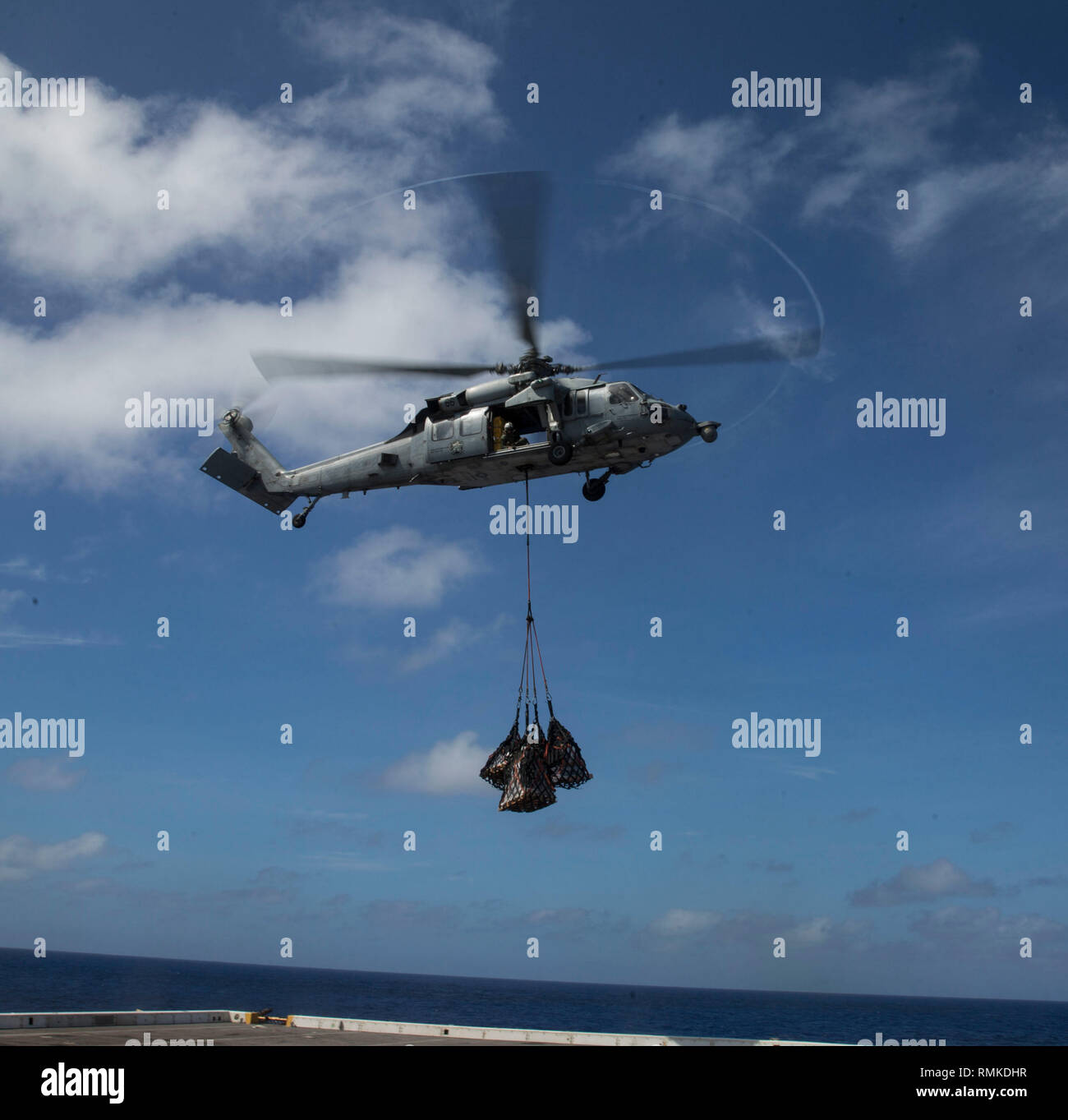 WESTERN PACIFIC (Feb. 7, 2019) A U.S. Navy SH-60 Sea Hawk with the 13th Marine Expeditionary Unit (MEU), conducts an aerial replenishment-at-sea aboard the San Antonio-class amphibious transport dock USS Anchorage (LPD 23) while on a deployment of the Essex Amphibious Ready Group (ARG) and 13th MEU. The Essex ARG/13th MEU is a capable and lethal Navy-Marine Corps team deployed to the U.S. 7th Fleet area of operations to support regional stability, reassure partners and allies and maintain a presence postured to respond to any crisis ranging from humanitarian assistance to contingency operation Stock Photo