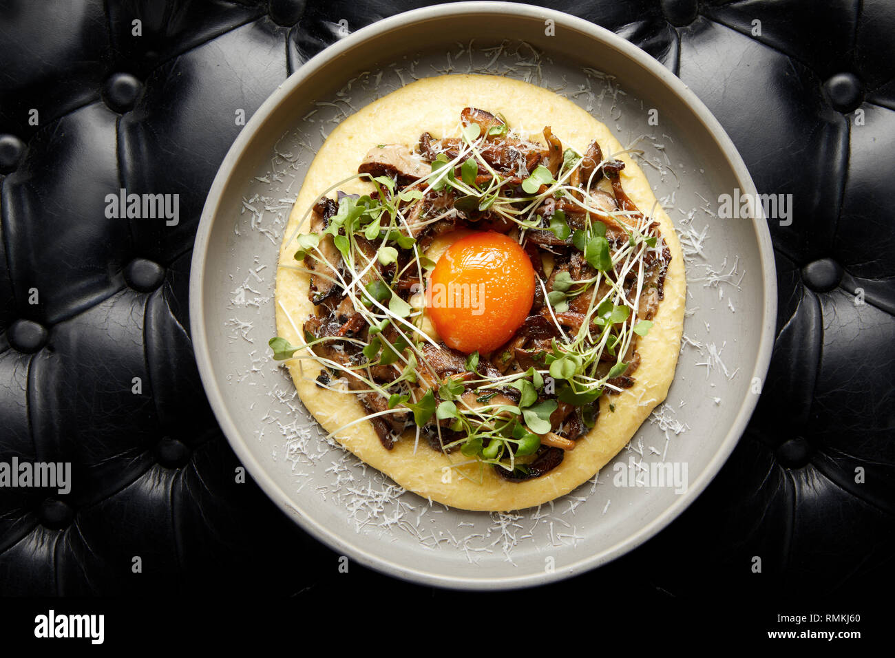 Top down photo of a creamy and rich starter dish made of mushrooms, potato puree and an egg yolk Stock Photo