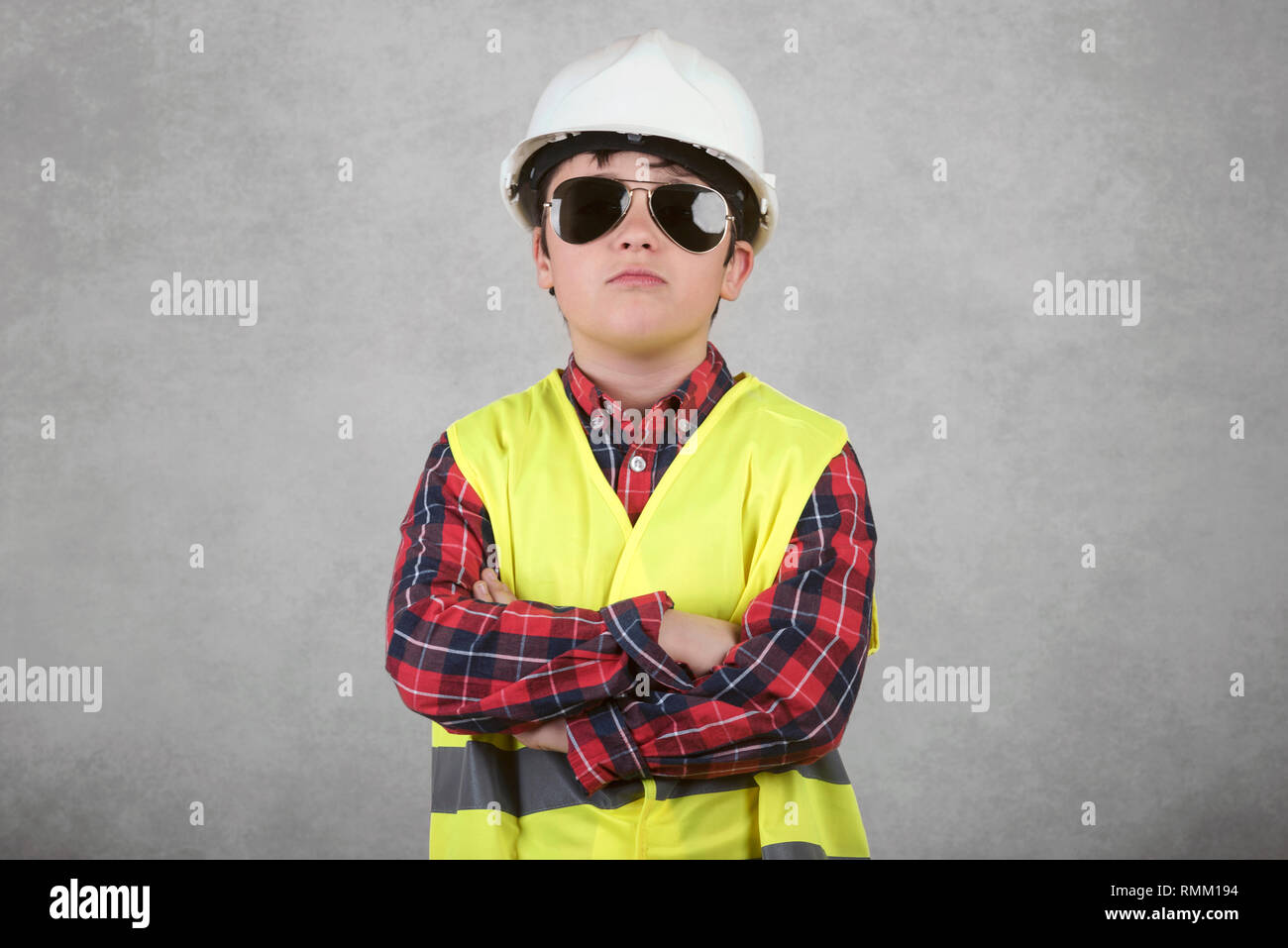 little child construction worker in White helmet and sunglasses against gray background Stock Photo