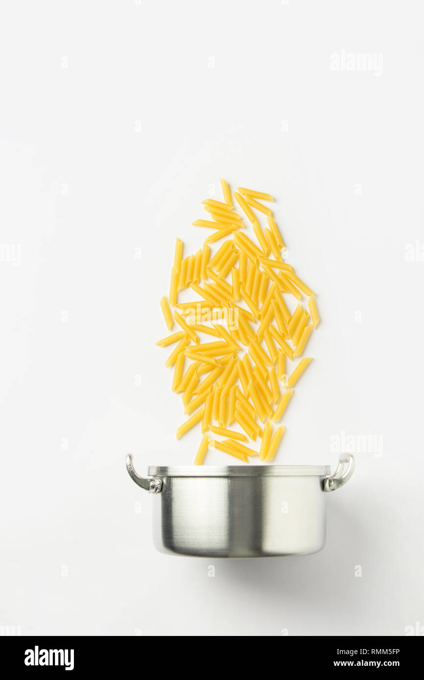 Creative food poster. Italian cuisine. Iron pot floating penne pasta in process of cooking on white background. Recipe template. Placeholder banner mo Stock Photo
