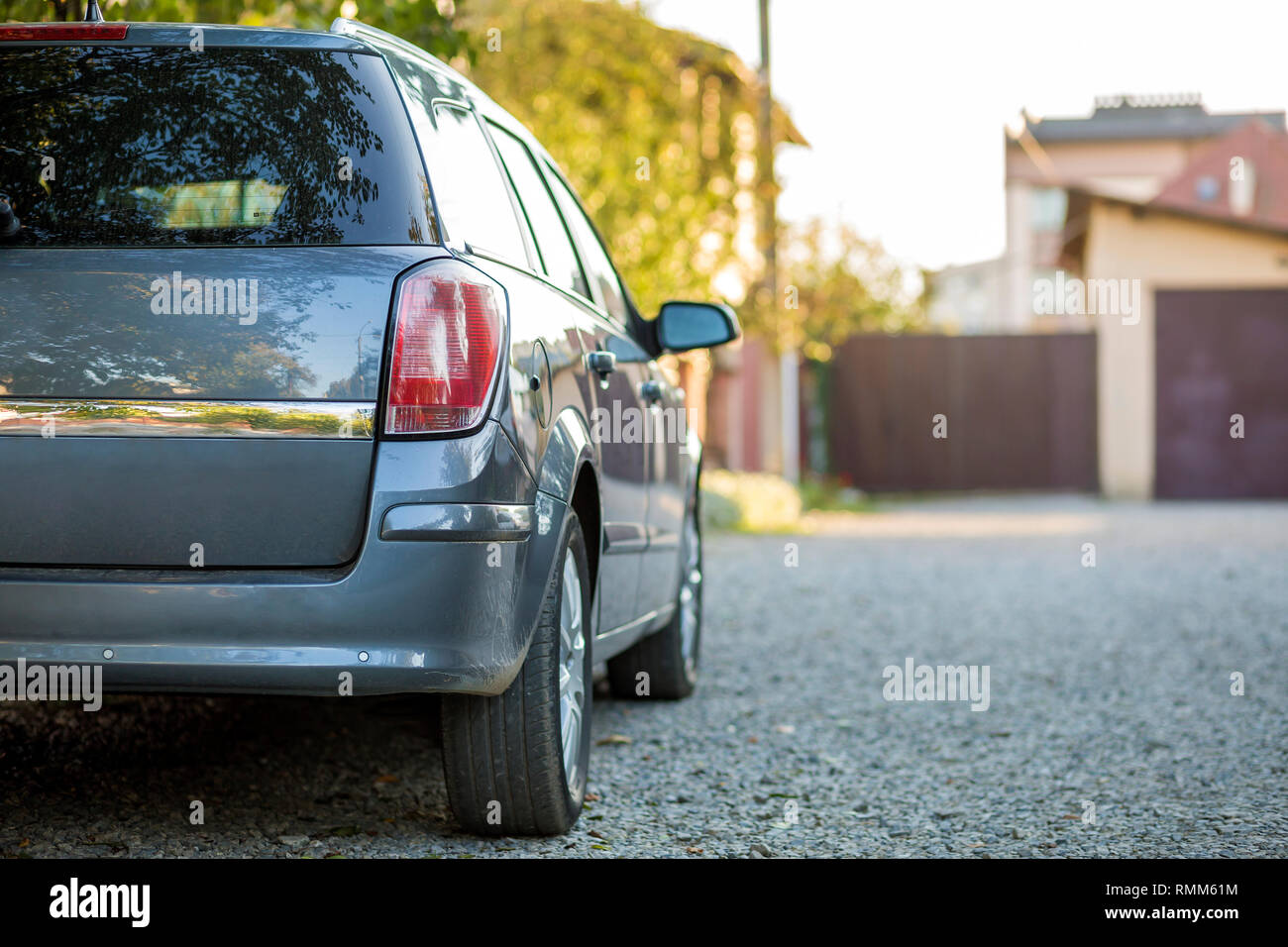 New shiny gray car parked on gravel suburbs road on blurred sunny summer background Stock Photo