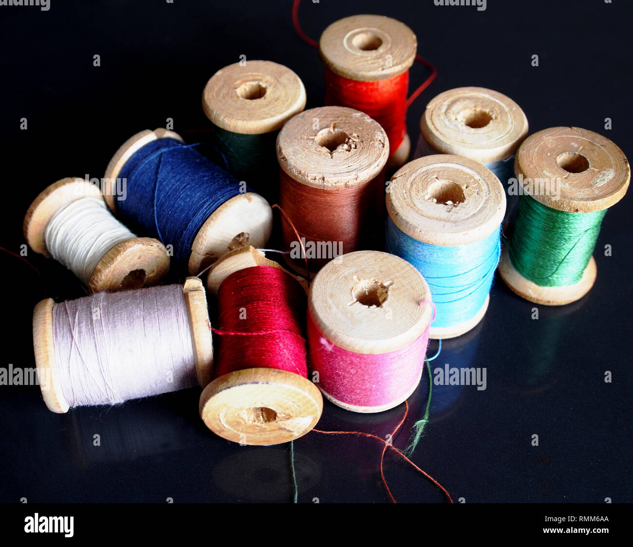 Natural silk threads on wooden spools of different colors. Stock Photo