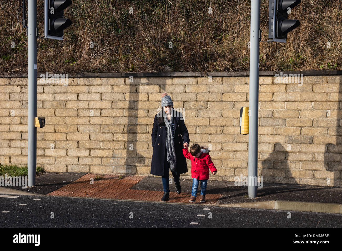 Mother and son crossing the road at traffic lights Stock Photo